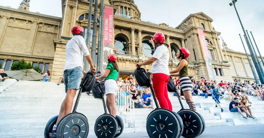 Un grupo pequeño en segway, con casco, en la explanada delante del Palau Nacional